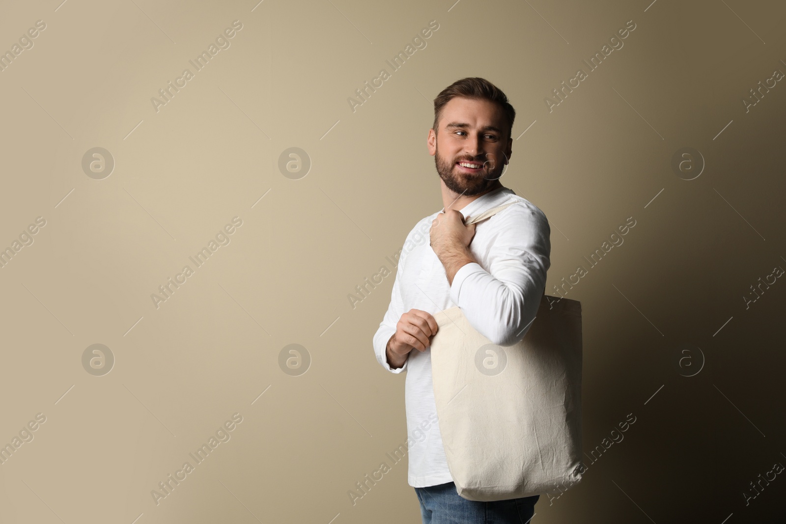 Photo of Happy young man with eco bag on beige background. Space for text