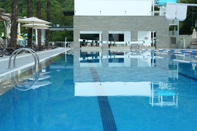 Photo of Outdoor swimming pool with ladder and handrails near building on sunny day