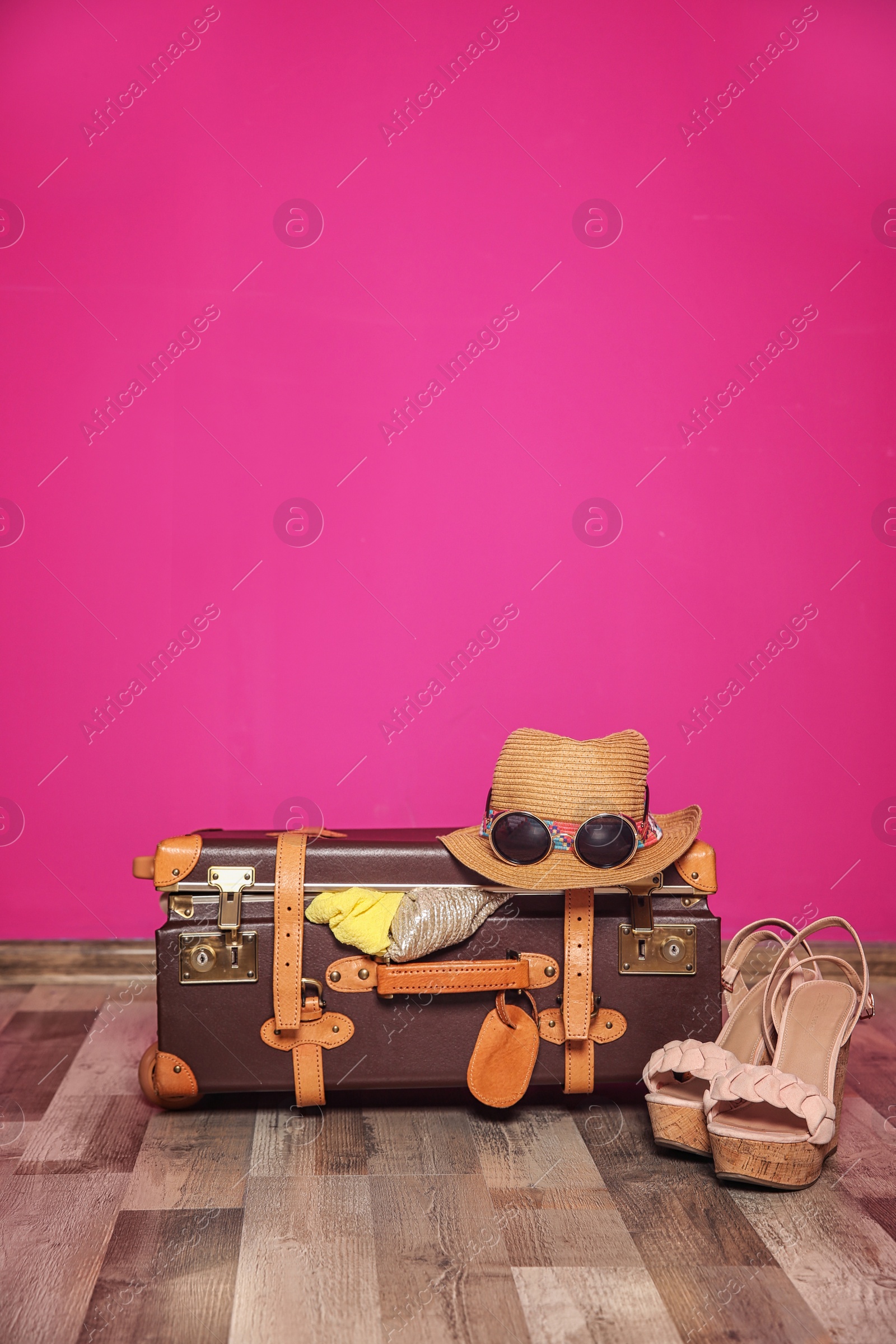 Photo of Suitcase packed for summer journey on floor near color wall