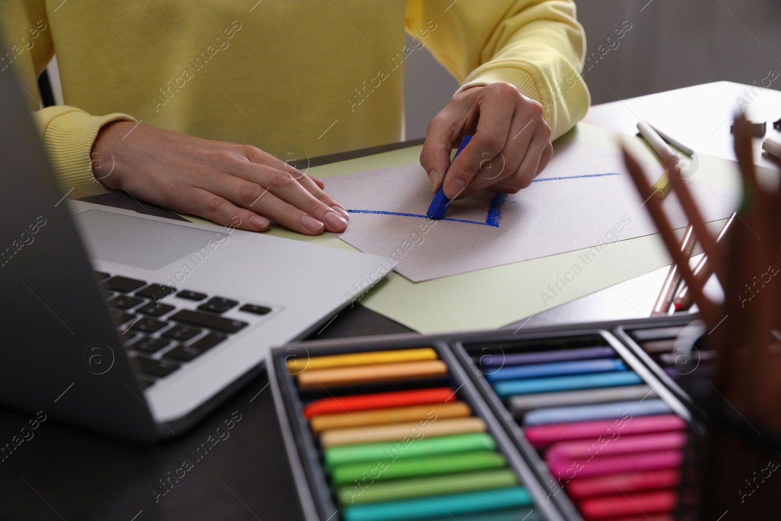 Photo of Artist drawing with soft pastels at table indoors, closeup