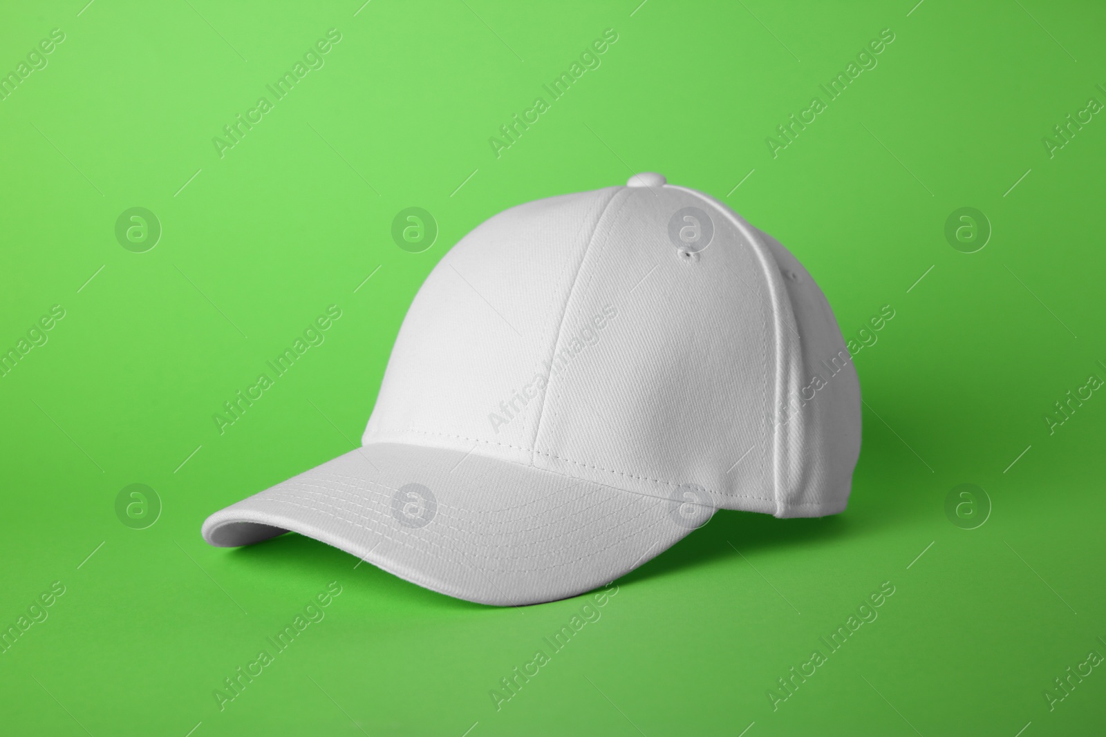 Photo of Stylish white baseball cap on light green background