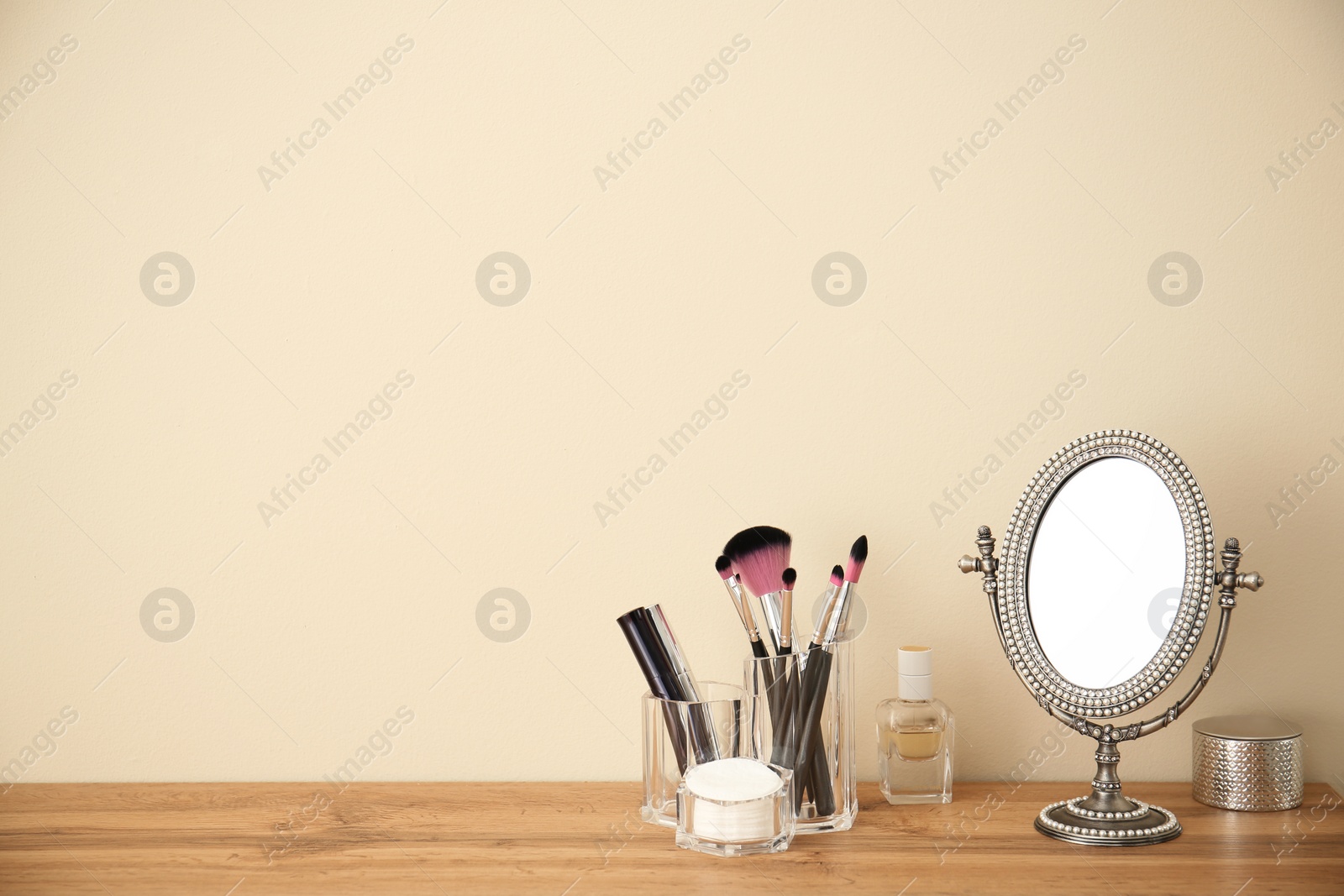 Photo of Makeup cosmetic products and tools in organizer on dressing table near color wall with space for text