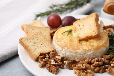 Photo of Tasty baked camembert, croutons and walnuts on table, closeup