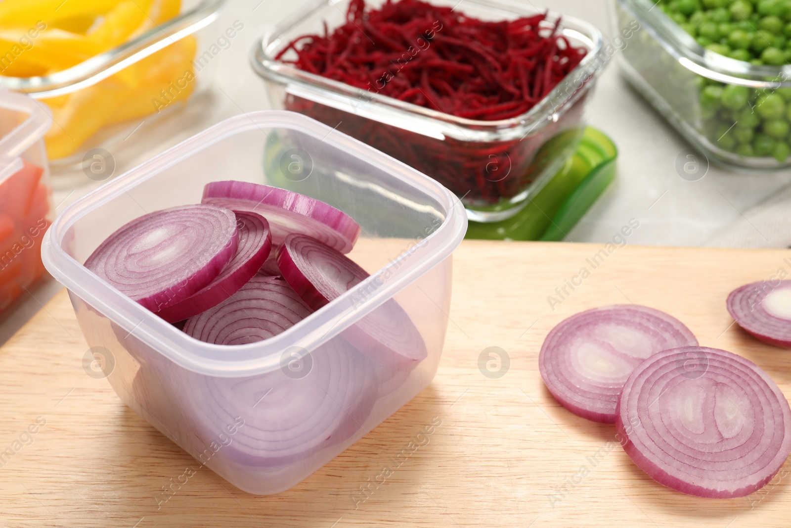 Photo of Containers with cut onion and fresh products on table, closeup. Food storage