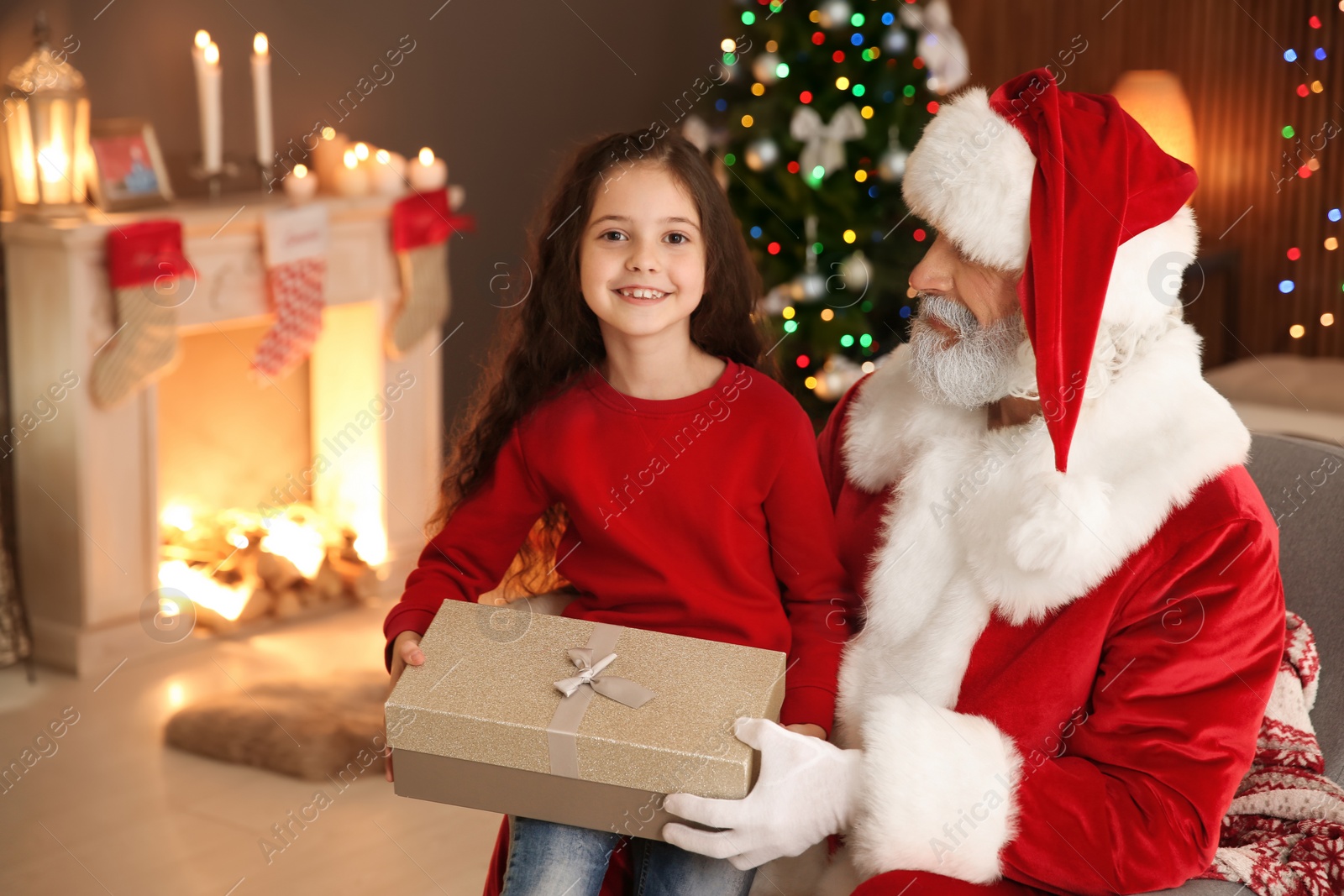 Photo of Little child with Santa Claus and Christmas gift at home