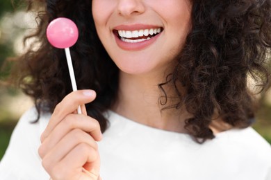 Photo of Woman with tasty lollipop outdoors, closeup view