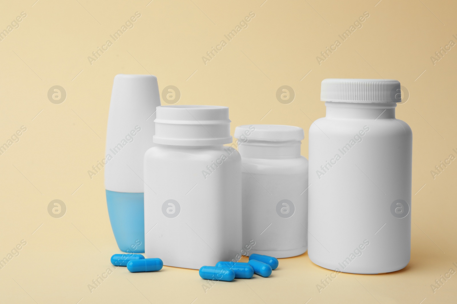 Photo of Containers and scattered pills on color background