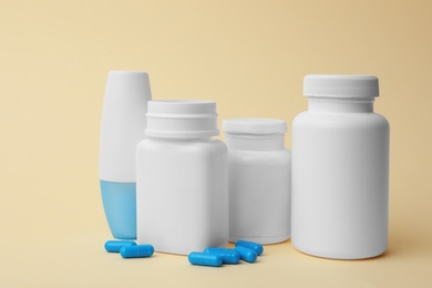 Photo of Containers and scattered pills on color background