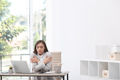 Photo of Young woman suffering from cold in office. Air conditioner malfunction