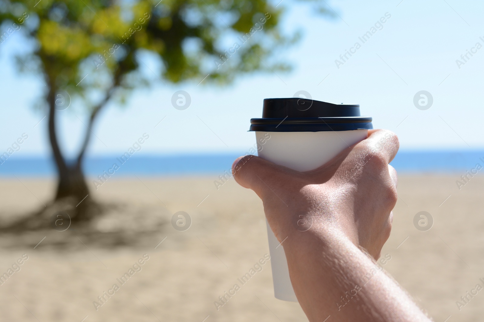 Photo of Woman with takeaway coffee cup on beach, closeup. Space for text