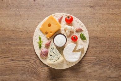 Composition with pizza crust and fresh ingredients on wooden table, top view