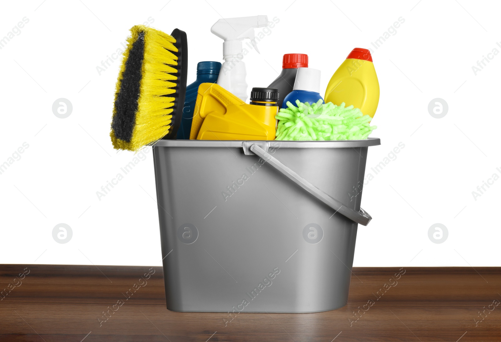 Photo of Grey bucket with car care products on wooden table against white background