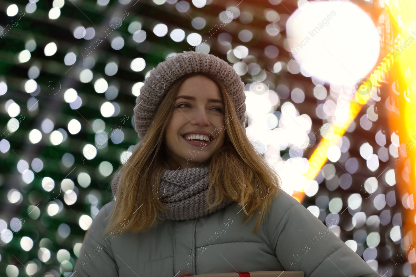 Photo of Happy young woman near festive lights. Christmas celebration