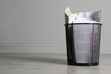 Photo of Metal bin with newspapers near white wall indoors, space for text. Rubbish recycling
