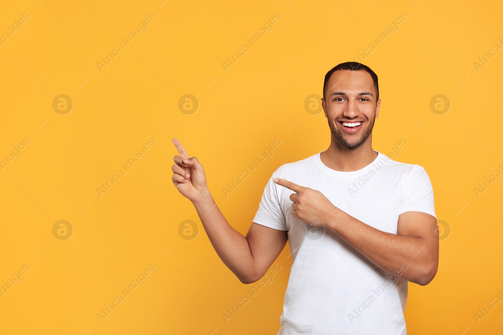 Photo of Portrait of happy African American man on orange background. Space for text