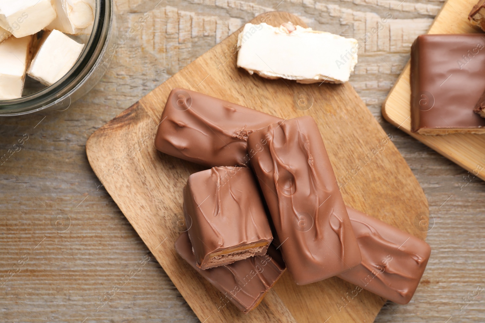 Photo of Tasty chocolate bars and nougat on wooden table, flat lay