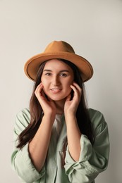 Photo of Smiling young woman in stylish outfit on light background