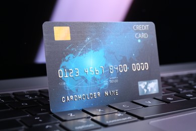 Photo of One plastic credit card on laptop, closeup