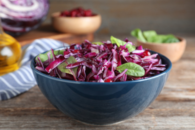 Photo of Fresh red cabbage salad served on wooden table, closeup