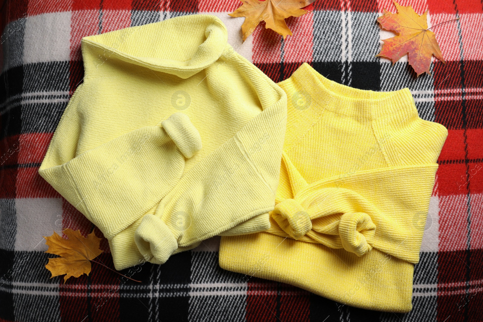 Photo of Beautiful yellow warm sweater and leaves on checkered plaid, flat lay