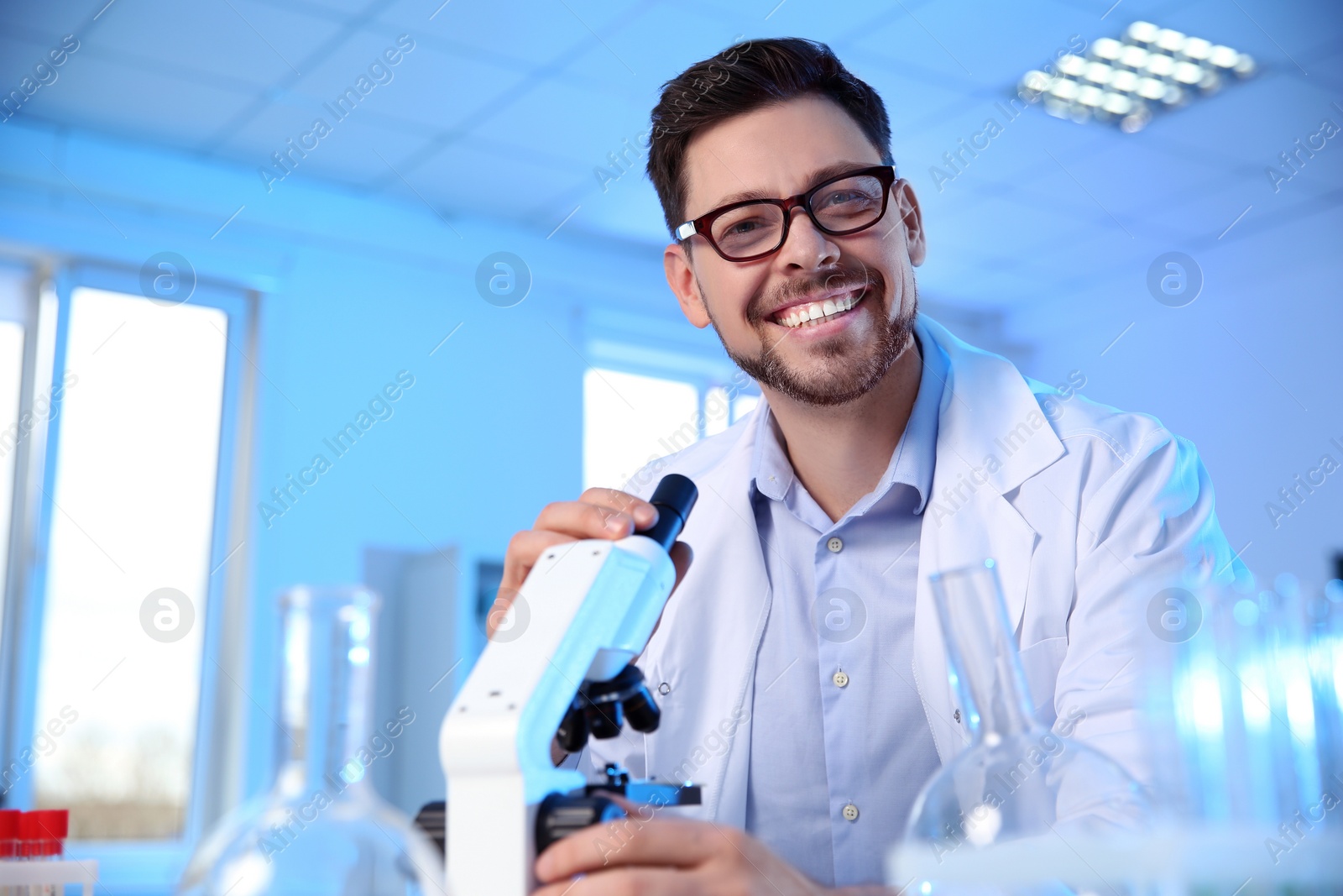 Photo of Male scientist with modern microscope in chemistry laboratory, space for text