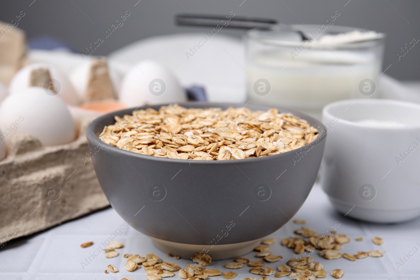 Photo of Different ingredients for cooking tasty oatmeal pancakes on white table, closeup