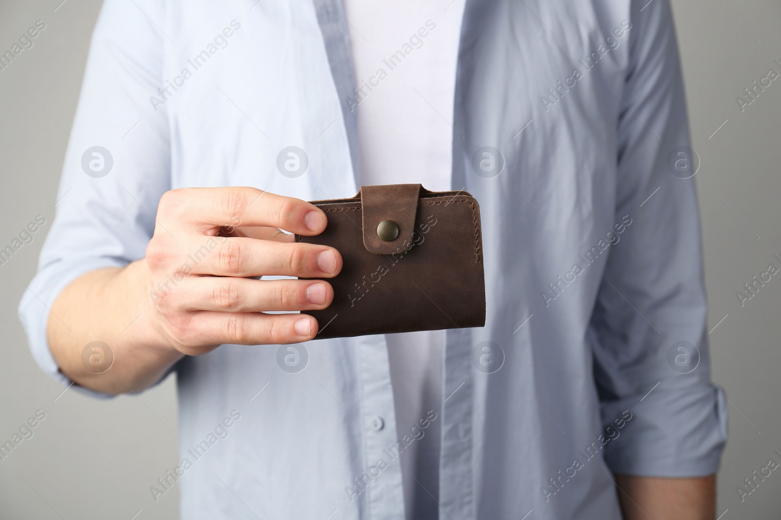 Photo of Man holding leather business card holder on grey background, closeup