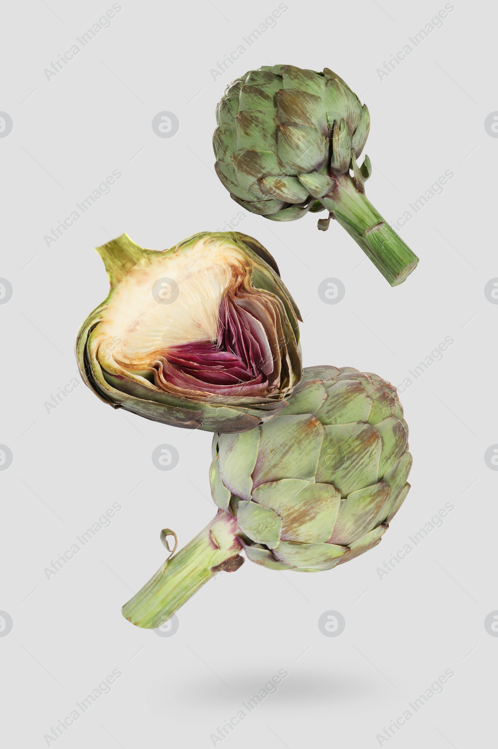 Image of Fresh raw artichokes falling on light grey background