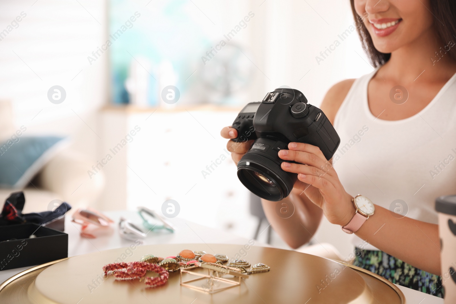 Photo of Young photographer taking picture of jewelry indoors, closeup