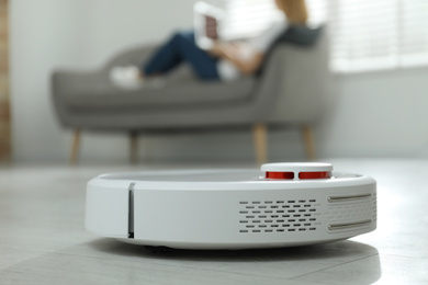 Woman resting while robotic vacuum cleaner doing her work at home