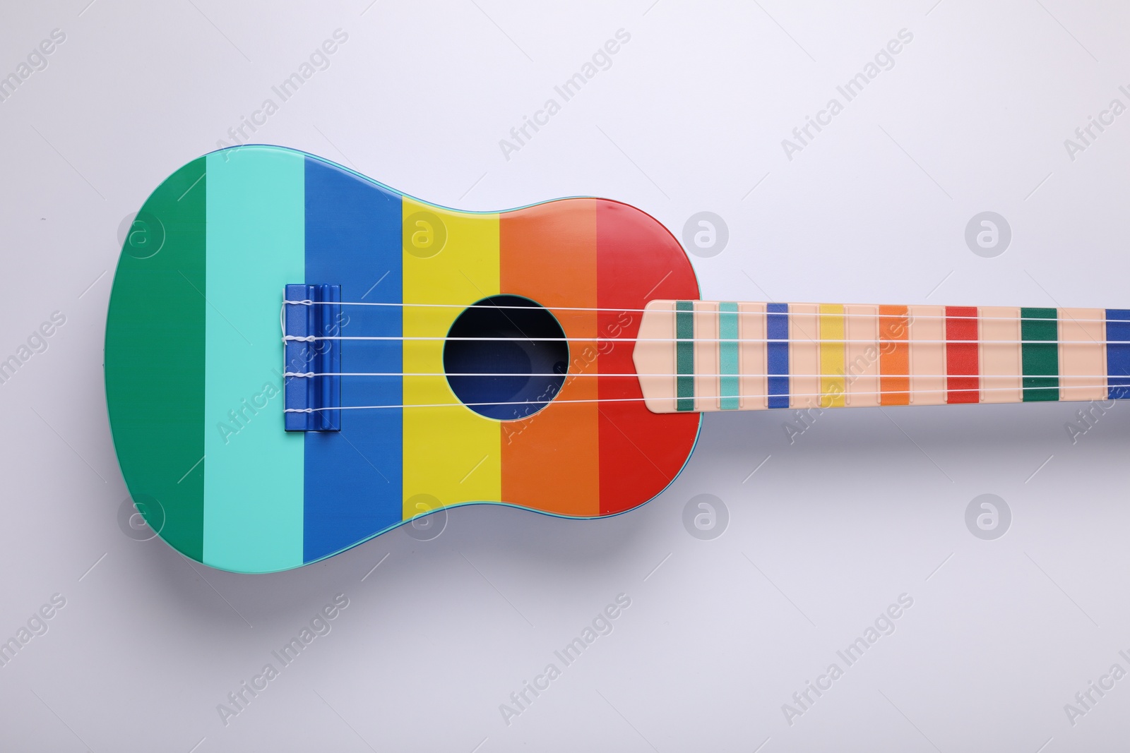 Photo of Colorful ukulele on white background, top view. String musical instrument