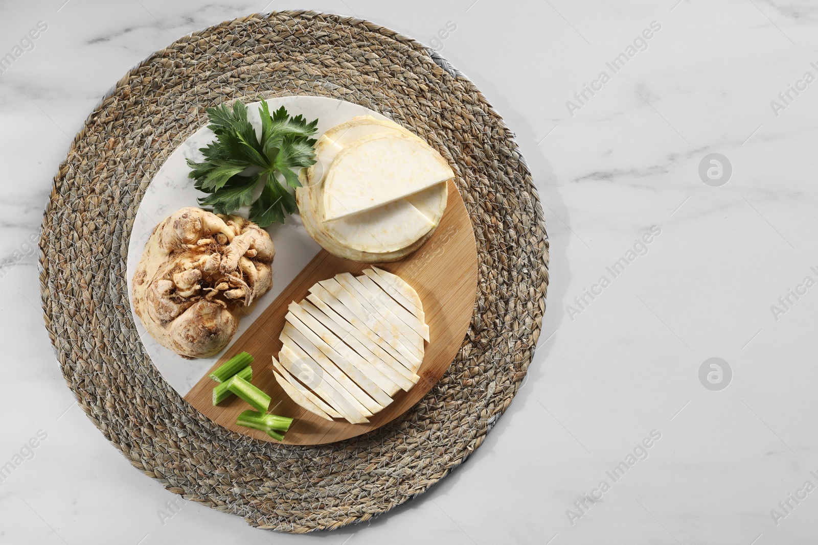 Photo of Whole and cut celery roots on white marble table, top view. Space for text