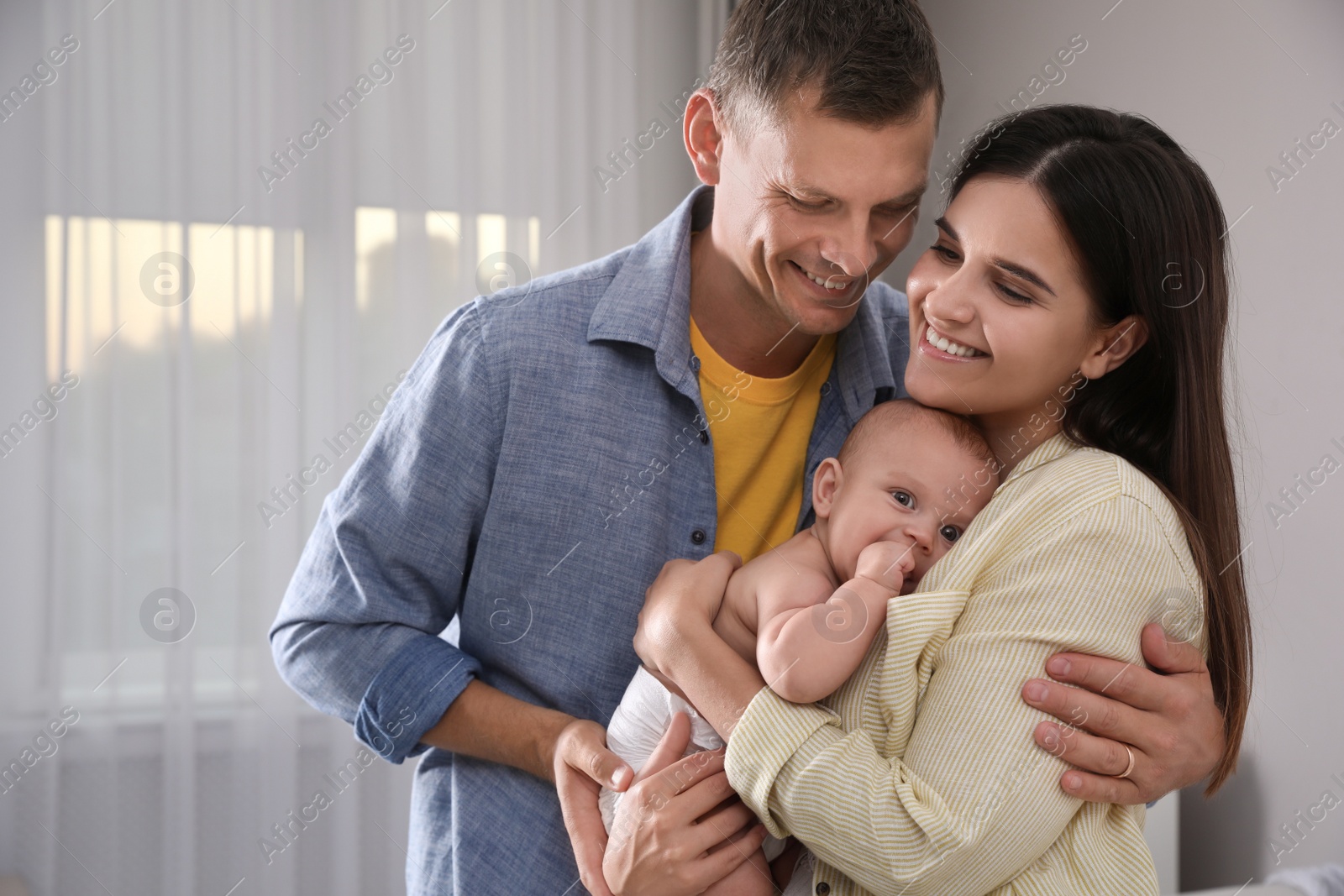 Photo of Happy family with their cute baby at home