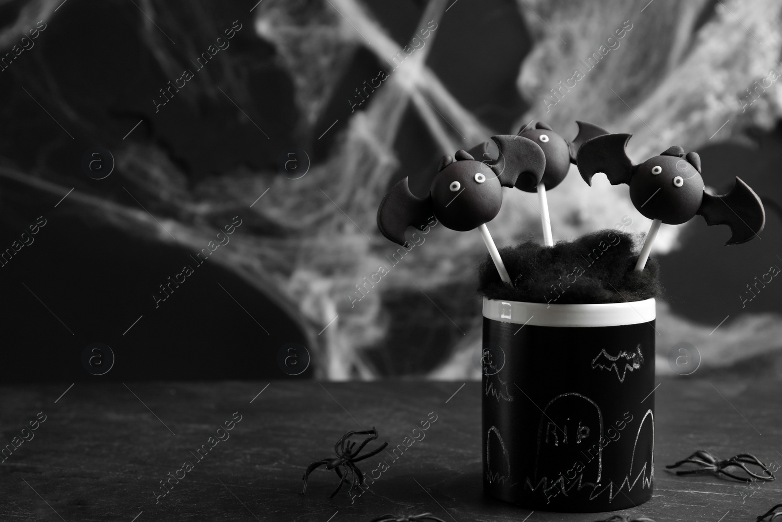Photo of Bat shaped cake pops on black table, space for text. Halloween treat