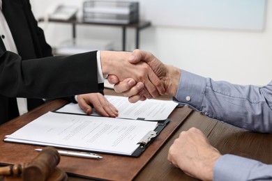 Lawyer shaking hands with client in office, closeup