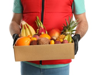Photo of Courier holding box with assortment of exotic fruits on white background, closeup