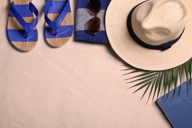 Photo of Beach towel, hat, sunglasses, book, tropical leaf and flip flops on sand, flat lay. Space for text