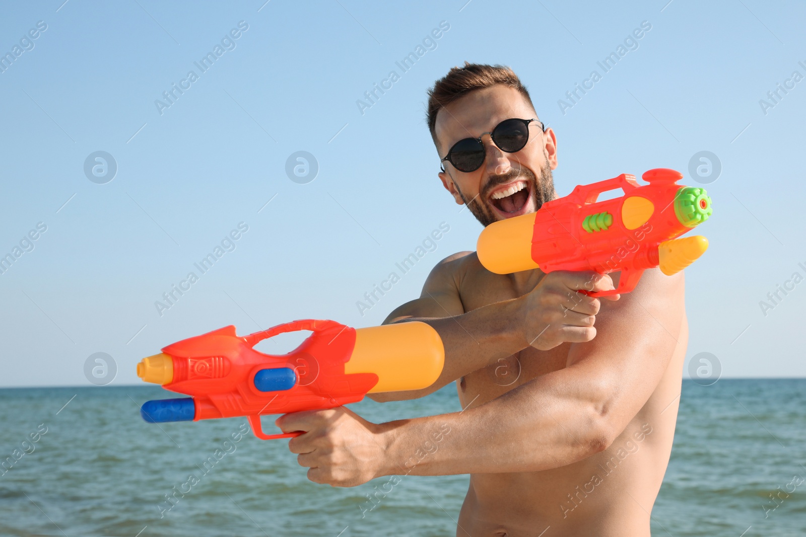 Photo of Man with water guns having fun on beach