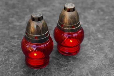 Photo of Red grave lanterns with burning candles on granite surface