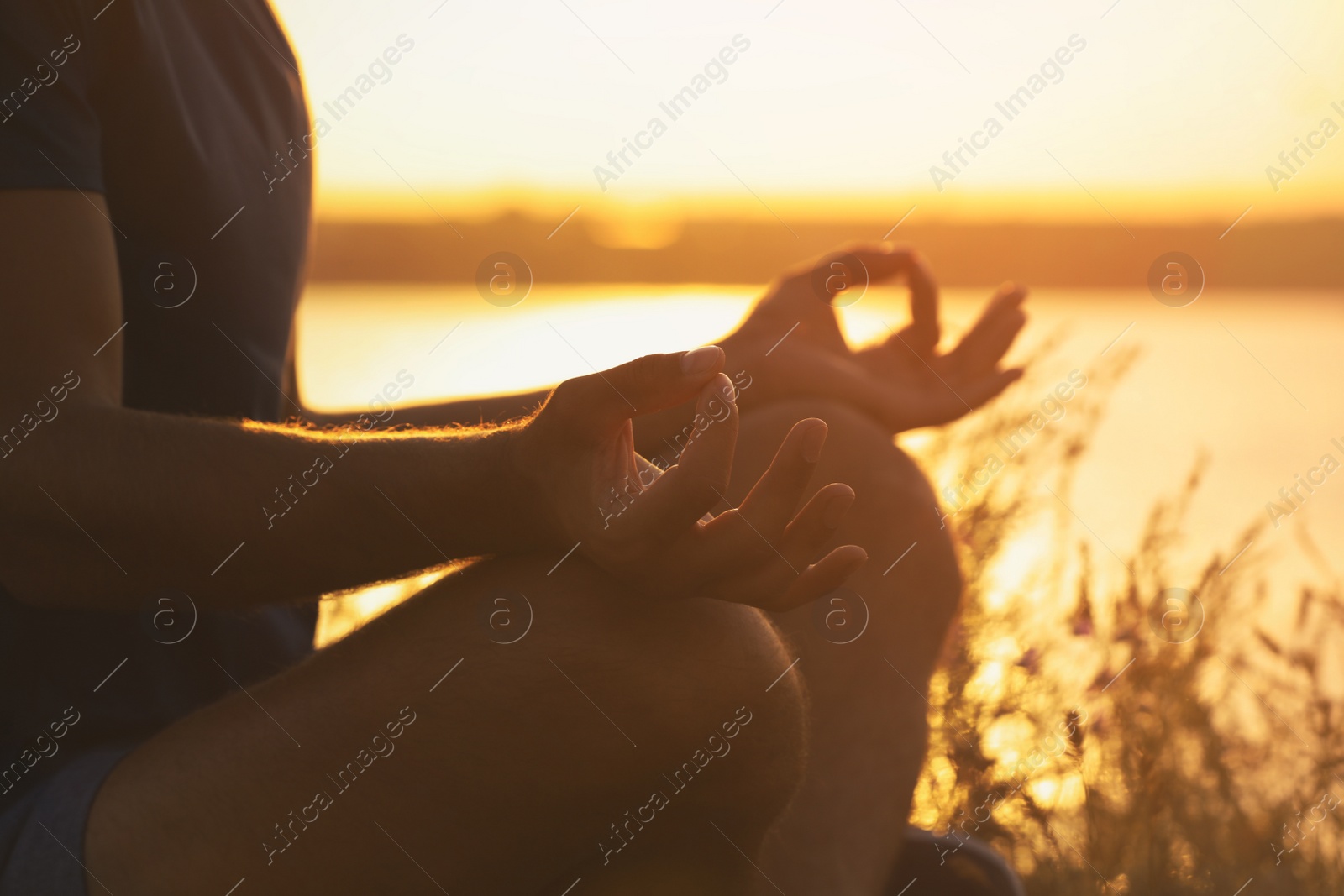 Photo of Man meditating near river at sunset, closeup