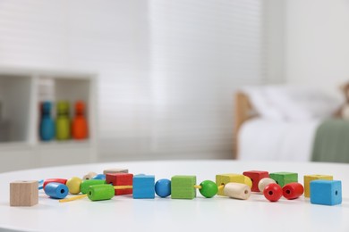 Photo of Motor skills development. Many colorful wooden pieces of playing set on white table indoors, space for text