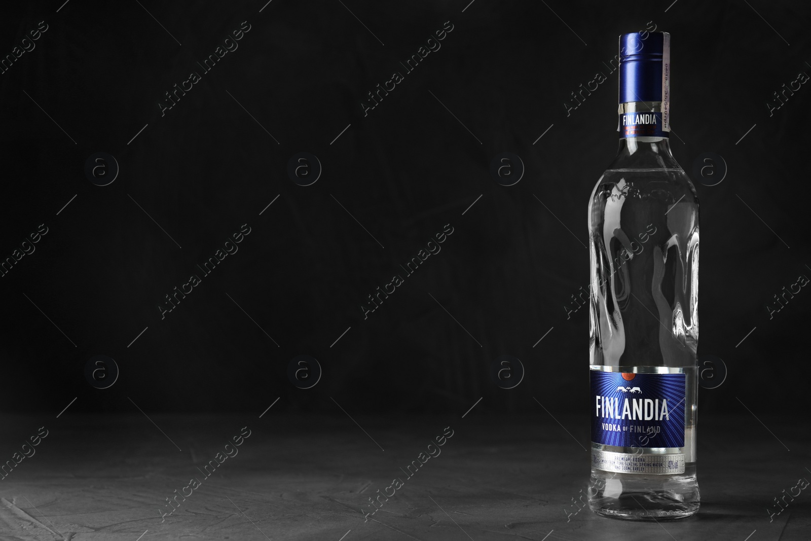 Photo of MYKOLAIV, UKRAINE - OCTOBER 03, 2019: Bottle of Finlandia vodka on table against dark background. Space for text