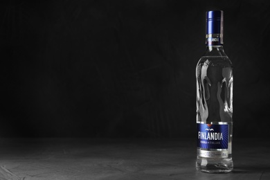 Photo of MYKOLAIV, UKRAINE - OCTOBER 03, 2019: Bottle of Finlandia vodka on table against dark background. Space for text