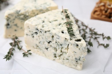 Tasty blue cheese with thyme on white table, closeup