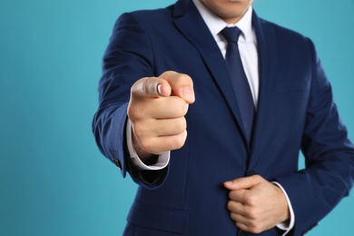 Photo of Businessman touching something on light blue background, closeup. Finger gesture
