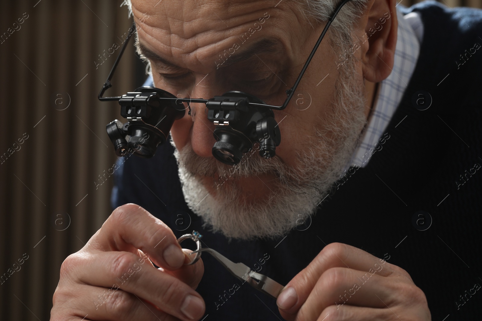 Photo of Professional jeweler working with ring on dark background, closeup