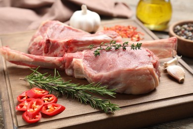 Photo of Fresh tomahawk beef cuts and spices on wooden table, closeup