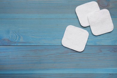 Photo of Clean cotton pads on light blue wooden table, flat lay. Space for text