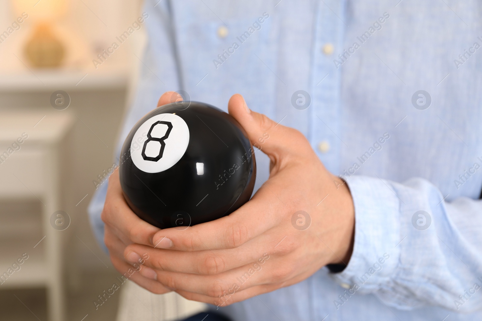 Photo of Man holding magic eight ball indoors, closeup