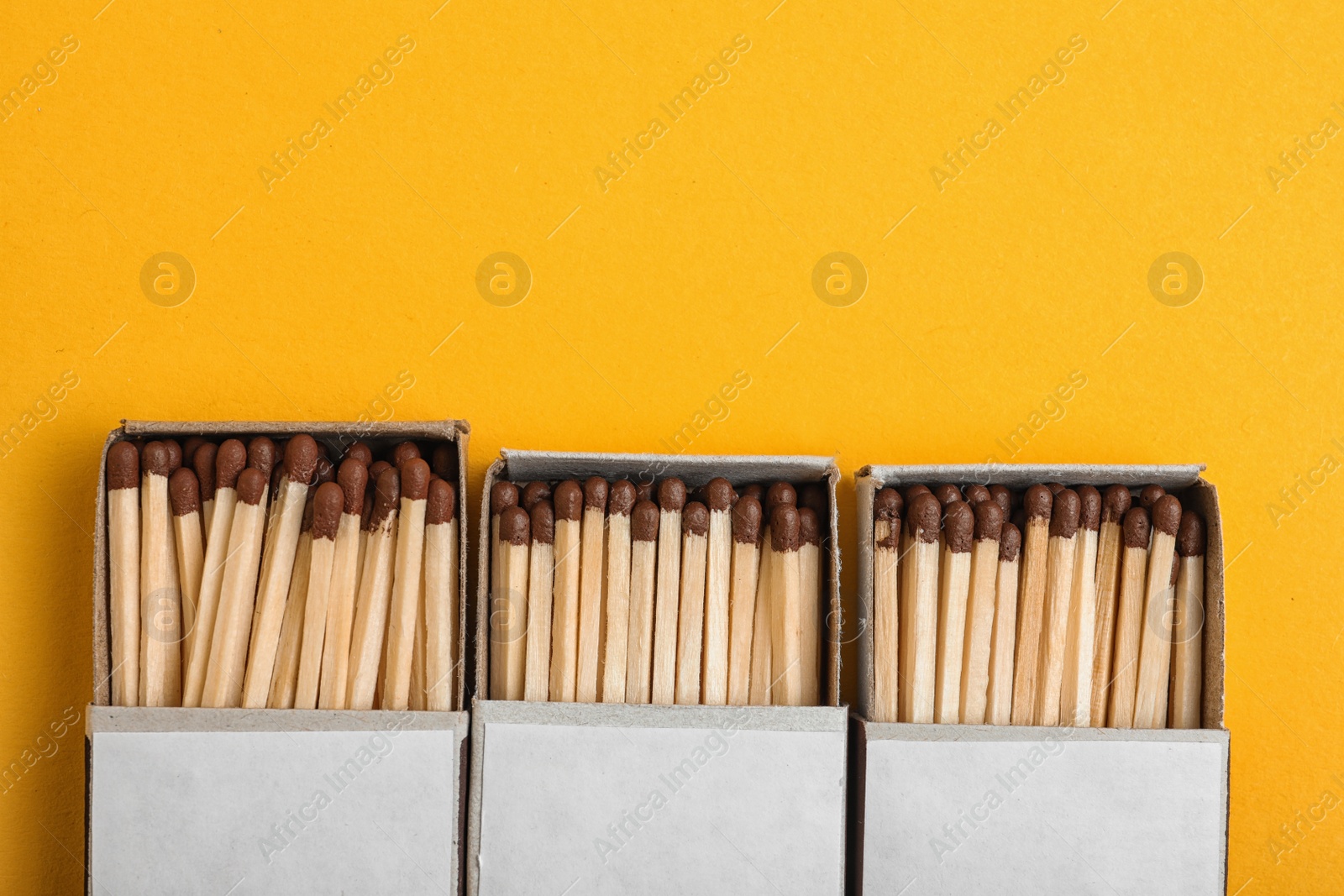 Photo of Cardboard boxes with matches on color background, flat lay. Space for text